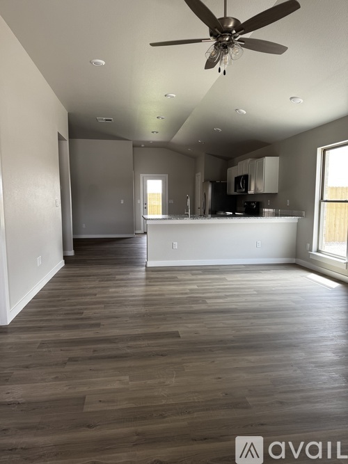 A spacious room with a ceiling fan and wooden flooring.