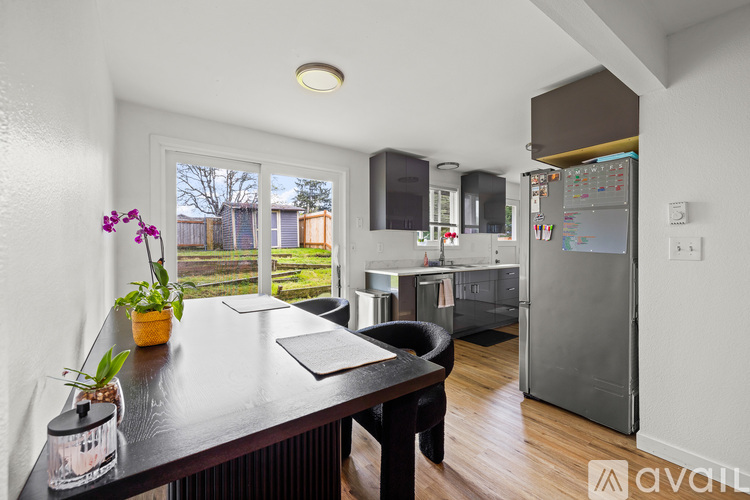 A kitchen with a refrigerator, sink, and a dining table with chairs.