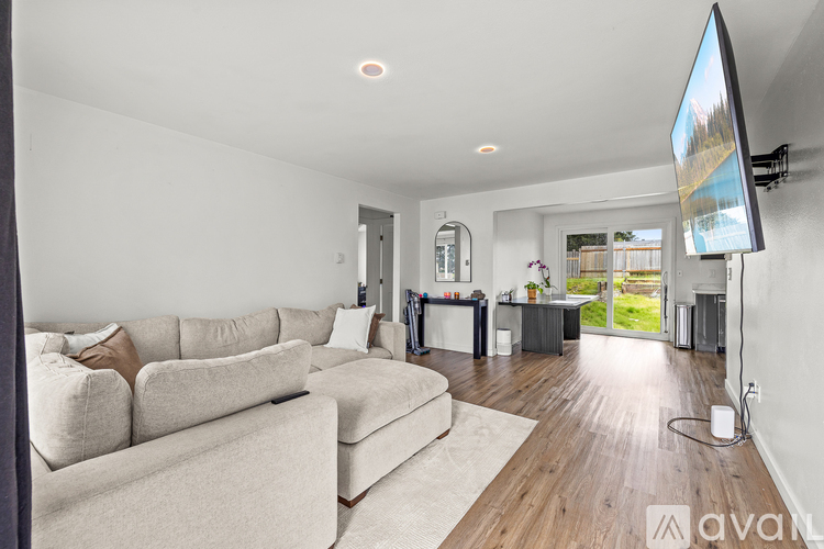 A living room with a white couch and a television on the wall.