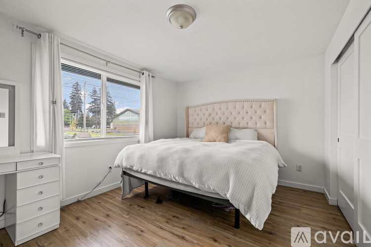 A bedroom with a bed, dresser, and window.