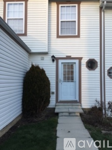 A white house with a blue door and a small window above it.
