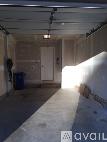 A large empty room with a door and a trash can.