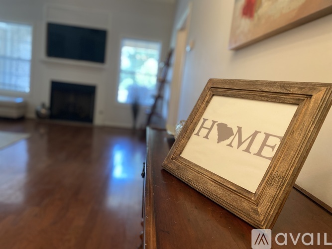 A picture frame with the word HOME on it sits on a wooden table.