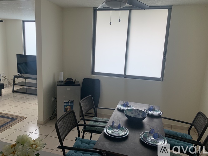 A dining room with a table set for two and a television in the corner.