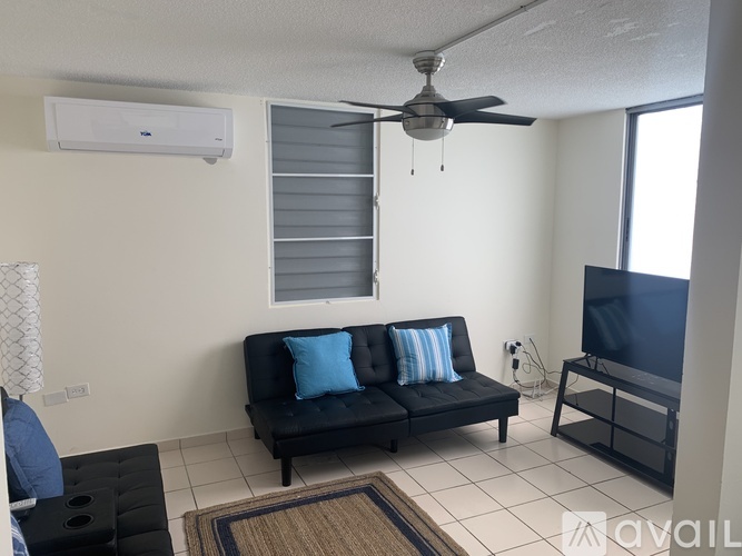 A living room with a black sofa and a ceiling fan.