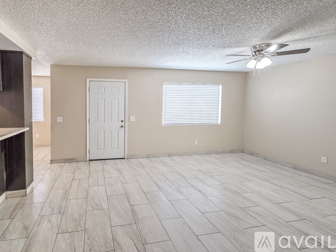 A room with a white door, a ceiling fan, and a tiled floor.