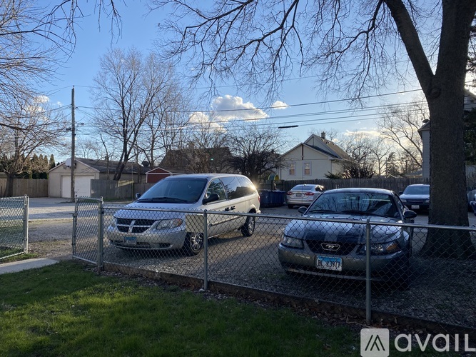 A silver van is parked behind a chain link fence.