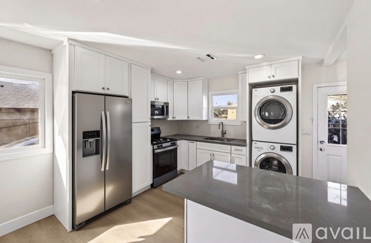 A modern kitchen with a stainless steel refrigerator and a washing machine built into the cabinetry.