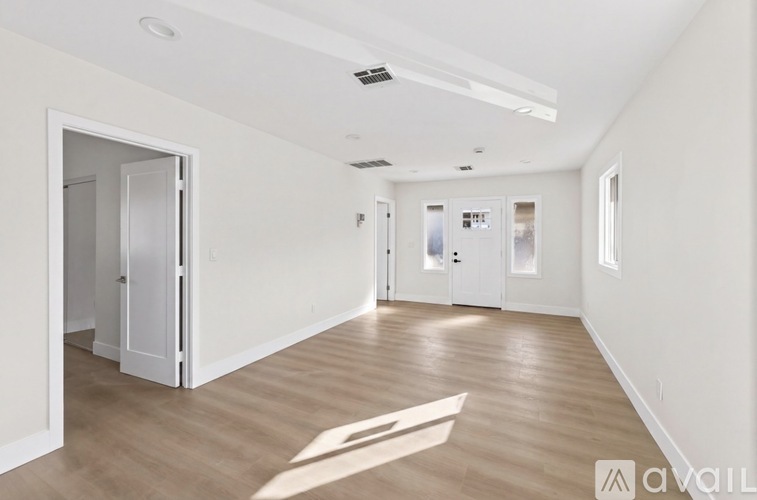 A spacious room with wooden flooring and white walls.