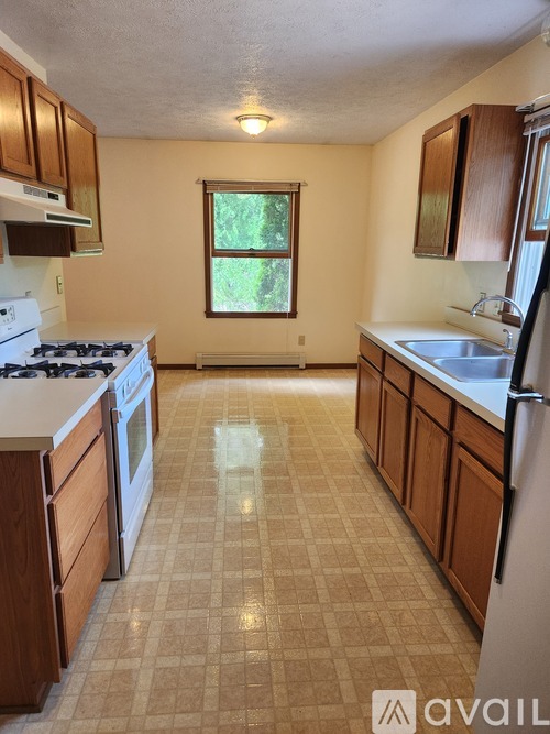 A kitchen with a tiled floor and wooden cabinets.