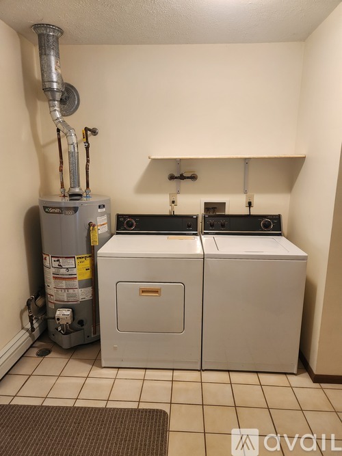 A wall-mounted water heater with a vent pipe and two outlets.