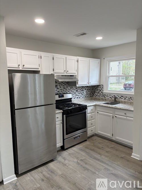 A kitchen with a stainless steel refrigerator and a black and white tiled backsplash.