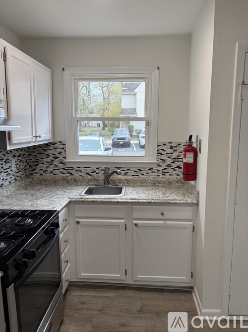 A kitchen with a black stove top oven and a white sink.
