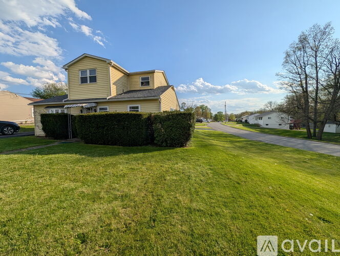 A house with a yellow exterior and a green lawn in front.