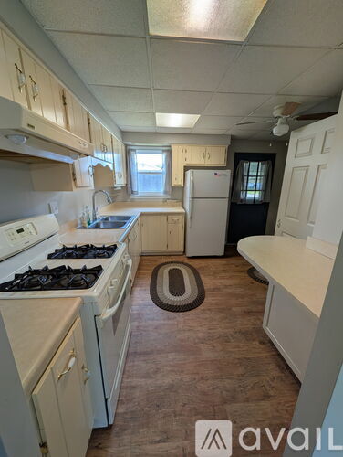 A kitchen with white appliances and wooden cabinets.