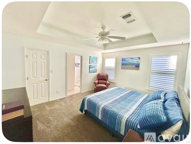 A bedroom with a bed, a chair, and a painting on the wall.