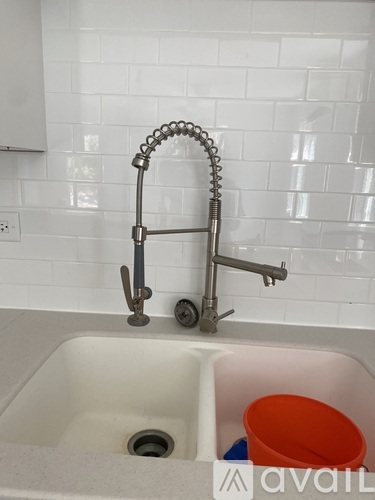 A kitchen sink with a faucet and a red bucket.