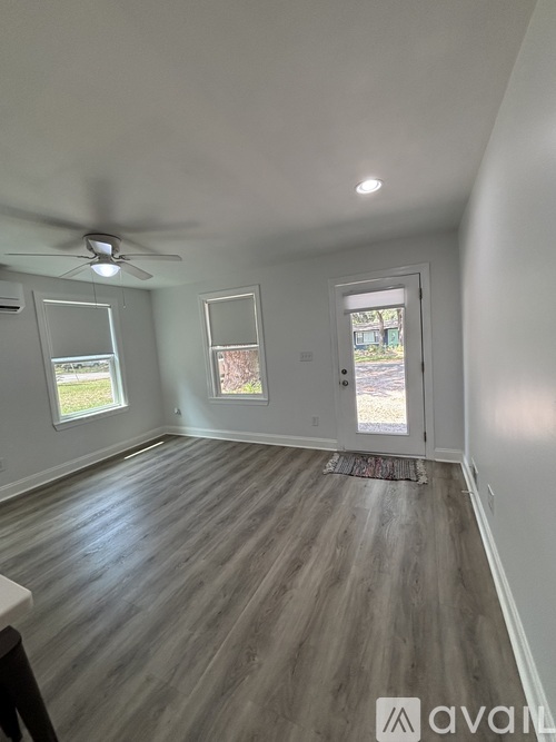 A room with a ceiling fan and wooden flooring.