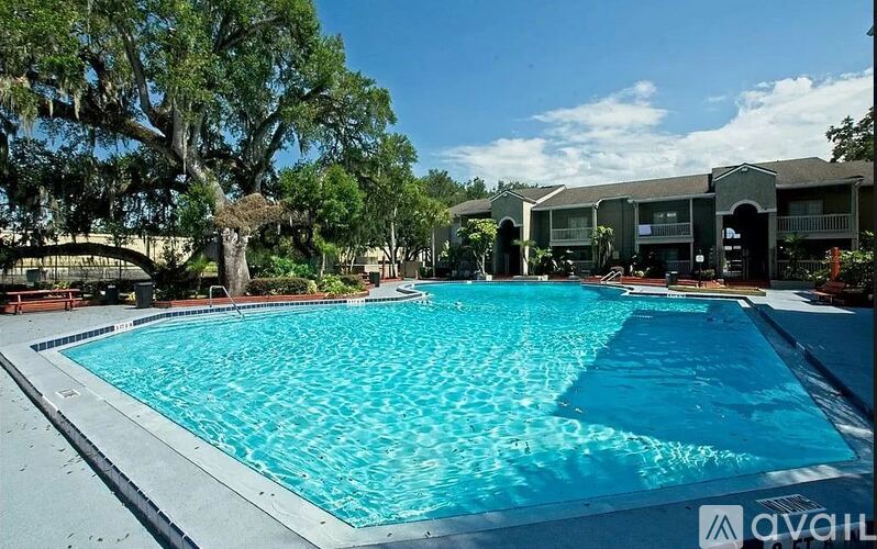 A large swimming pool surrounded by trees and a bridge.