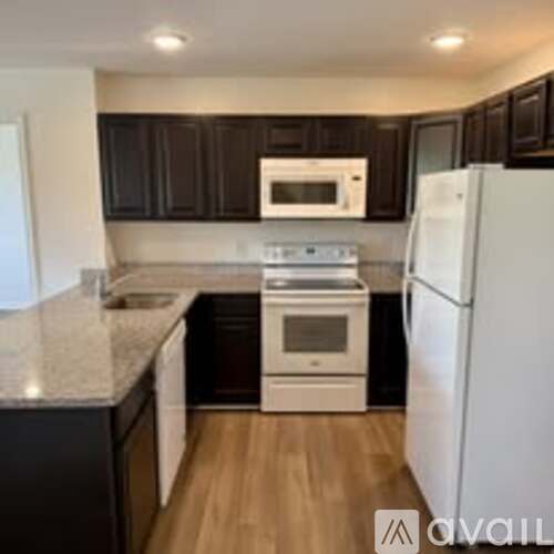 A kitchen with a white refrigerator, white stove, and white microwave.