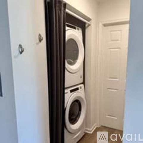 A washer and dryer are stacked on top of each other in a small laundry room.