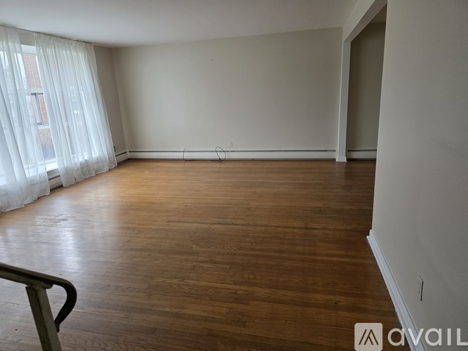 A spacious room with wooden flooring and white walls.