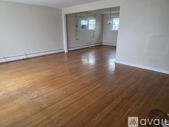 A room with wooden flooring and a window with blinds.