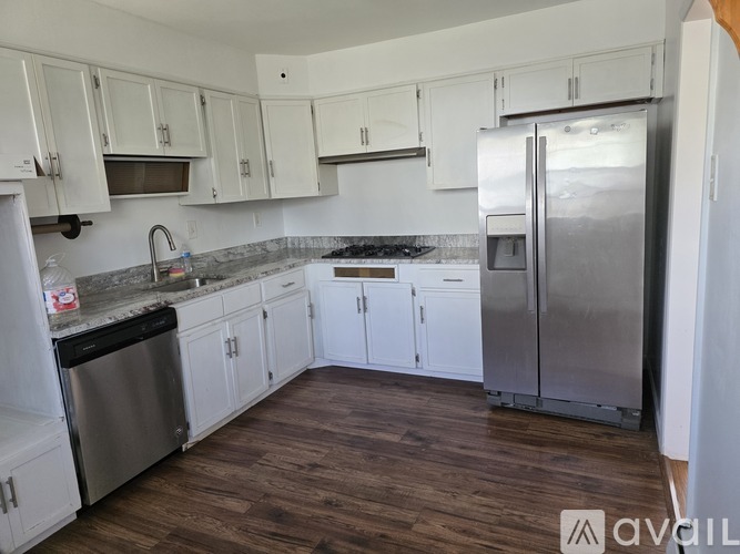 A kitchen with white cabinets and a wooden floor.