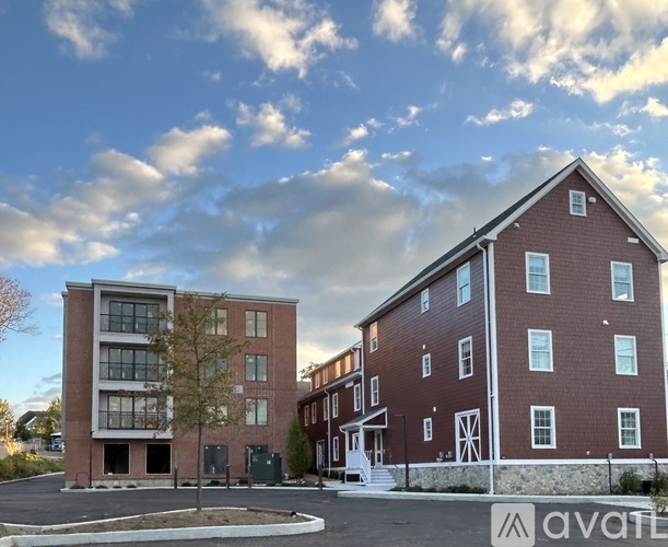 Two red brick buildings with white trim and windows, one with a white door and steps leading up to it.