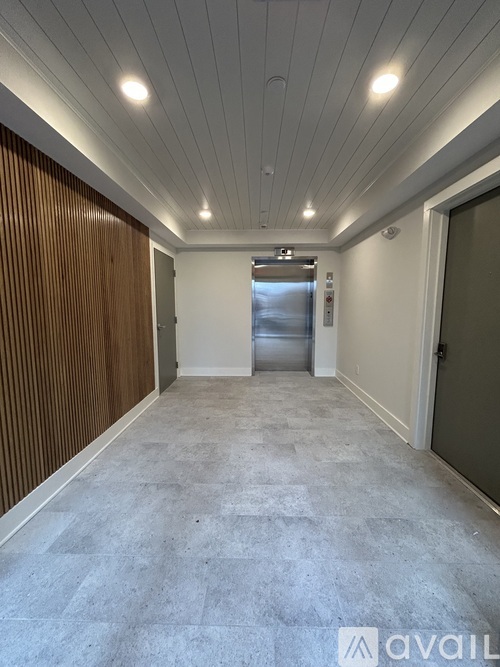 A long hallway with a wooden wall on the left and a metal elevator in the middle.