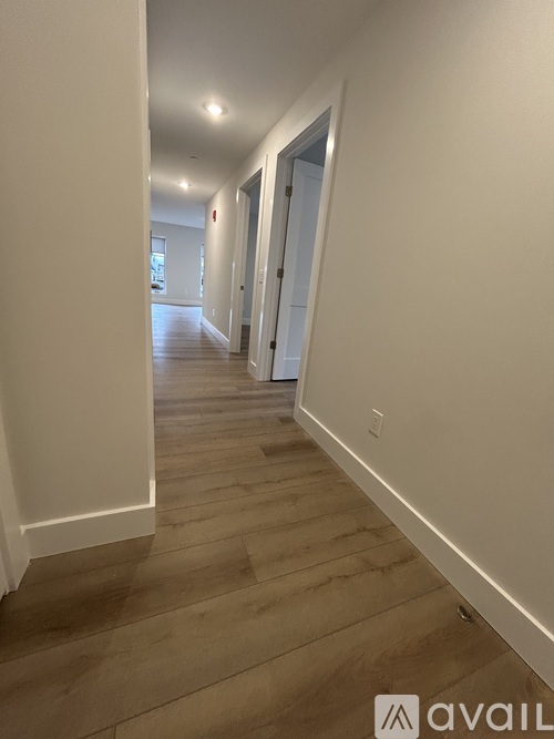 A long hallway with white walls and wooden floors.