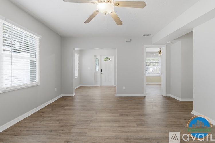A spacious room with wooden floors and a ceiling fan.