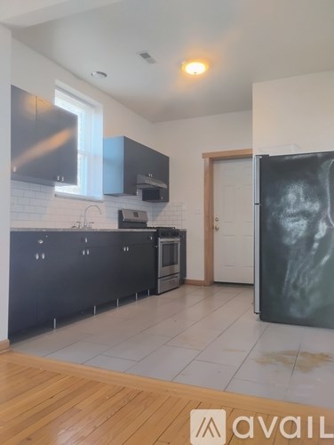 A kitchen with black cabinets and a wooden floor.