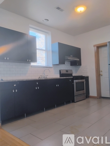 A kitchen with black cabinets and a white tiled backsplash.