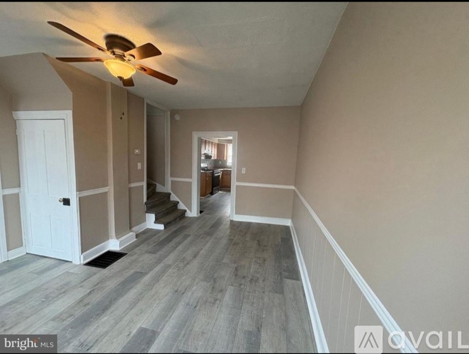 A spacious room with a fan and wooden flooring.