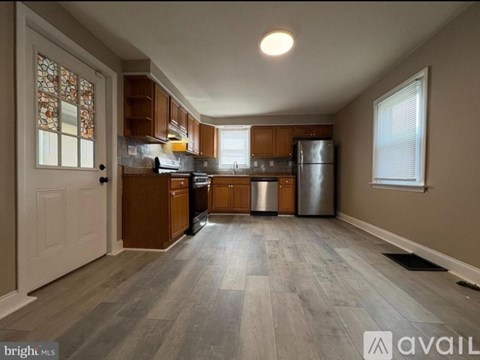 A kitchen with wooden cabinets and a stainless steel refrigerator.
