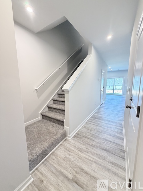 A hallway with a staircase and a door on the right.