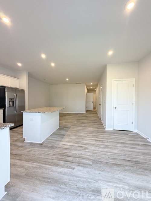 A spacious kitchen with a refrigerator, island, and a dining area with a table and chairs.