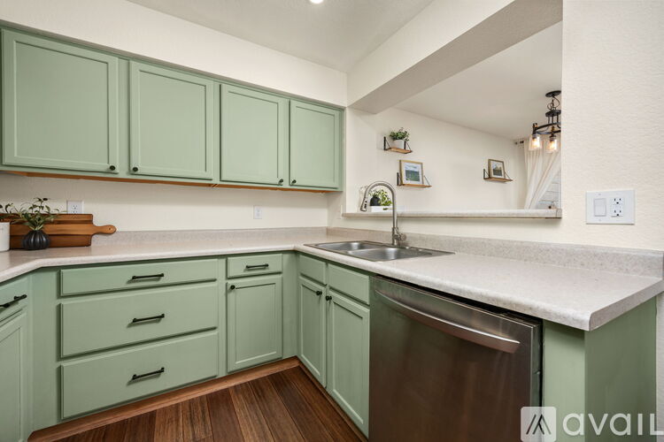 A kitchen with green cabinets and a stainless steel dishwasher.