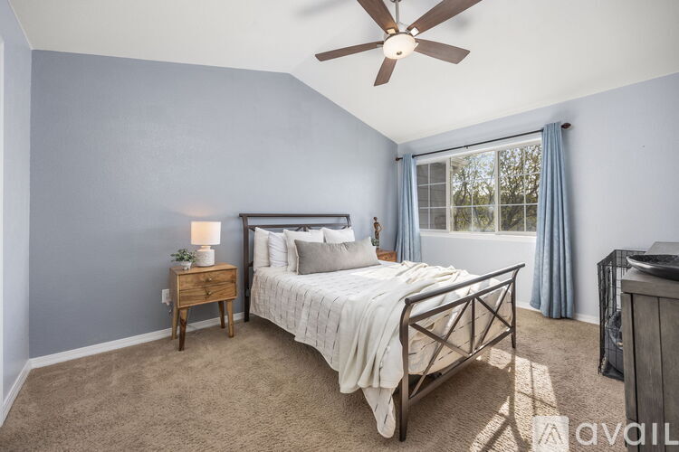 A bedroom with a bed, nightstand, and a ceiling fan.