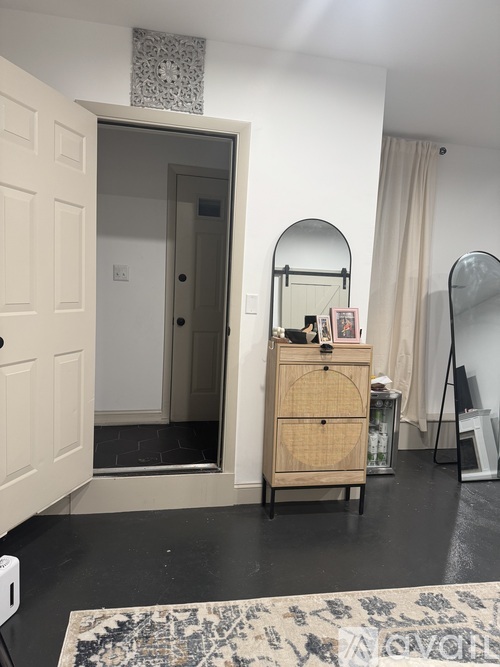 A room with a wooden cabinet and a mirror on a stand.