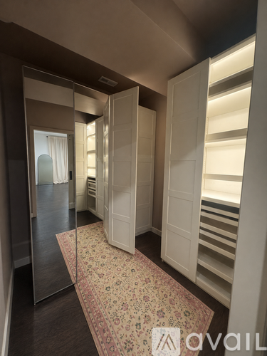 A hallway with a rug and a mirror on the wall.