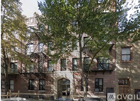 A tree in front of a building with a sign that says "available".