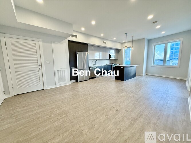 A spacious room with a kitchen area and a large window.
