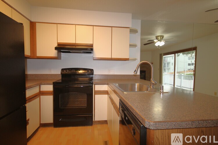 A kitchen with a black refrigerator and an oven with a stove top.