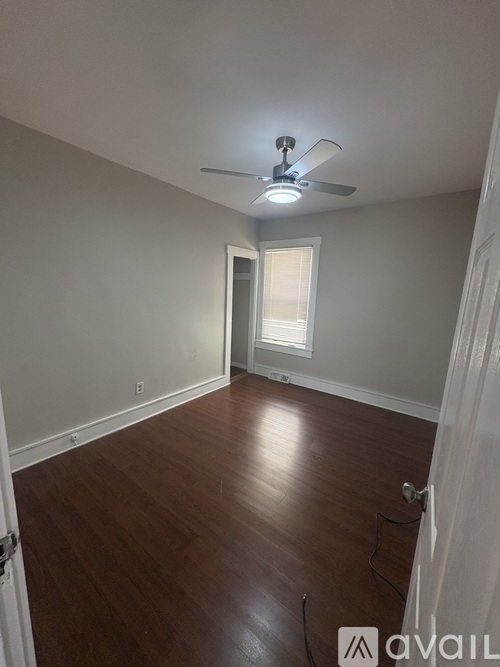 A room with a ceiling fan and wooden flooring.