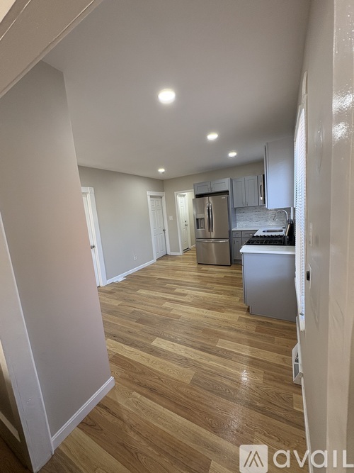 A kitchen area with wooden flooring and white walls.