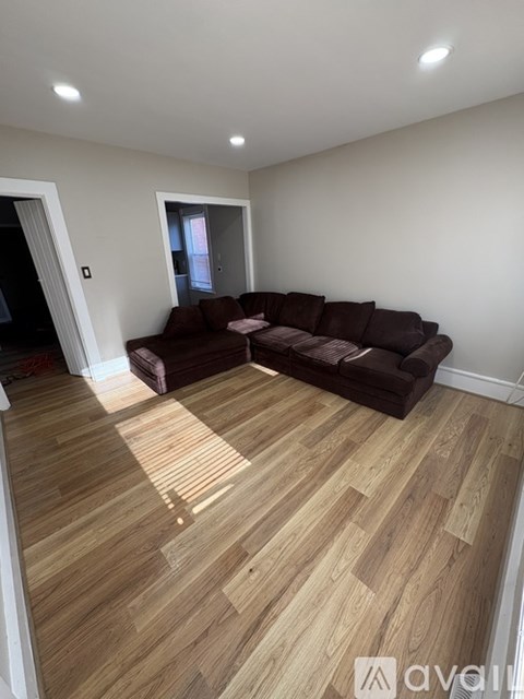 A living room with a brown couch and wooden flooring.