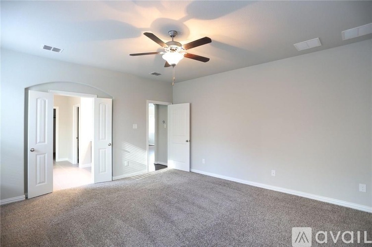 A spacious room with a ceiling fan and carpeted floor.