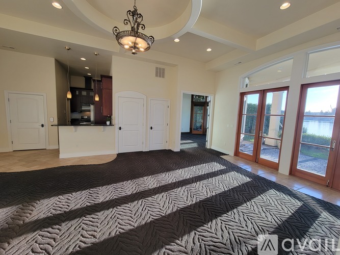 A large, empty room with a chandelier and a patterned carpet.